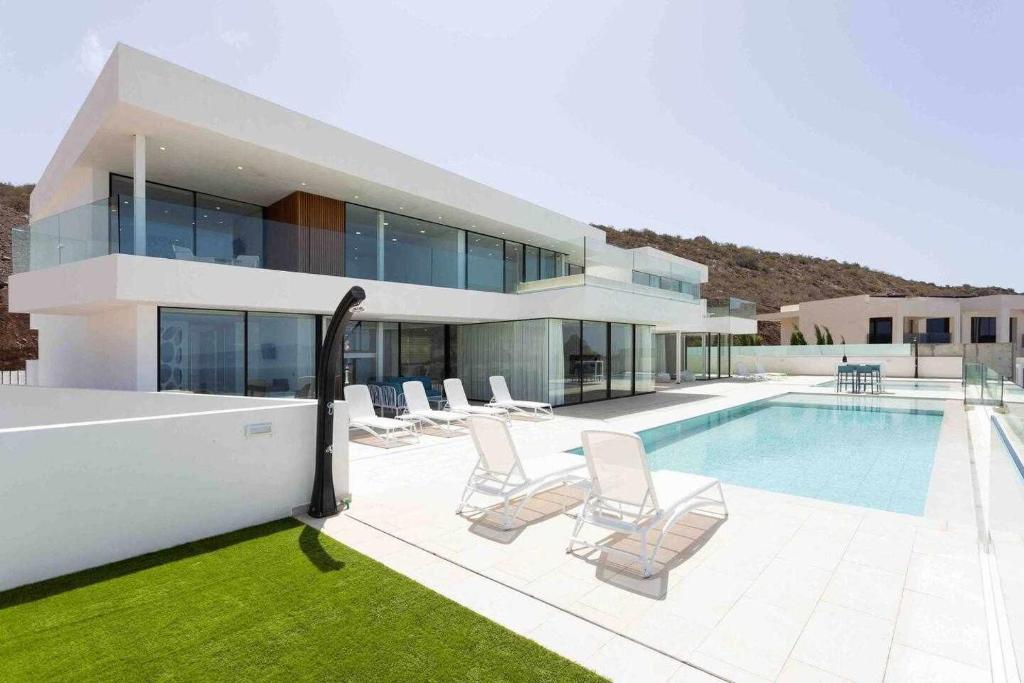 een groot huis met een zwembad en stoelen bij New Home Costa Adeje Luxurious Private Villa in Adeje