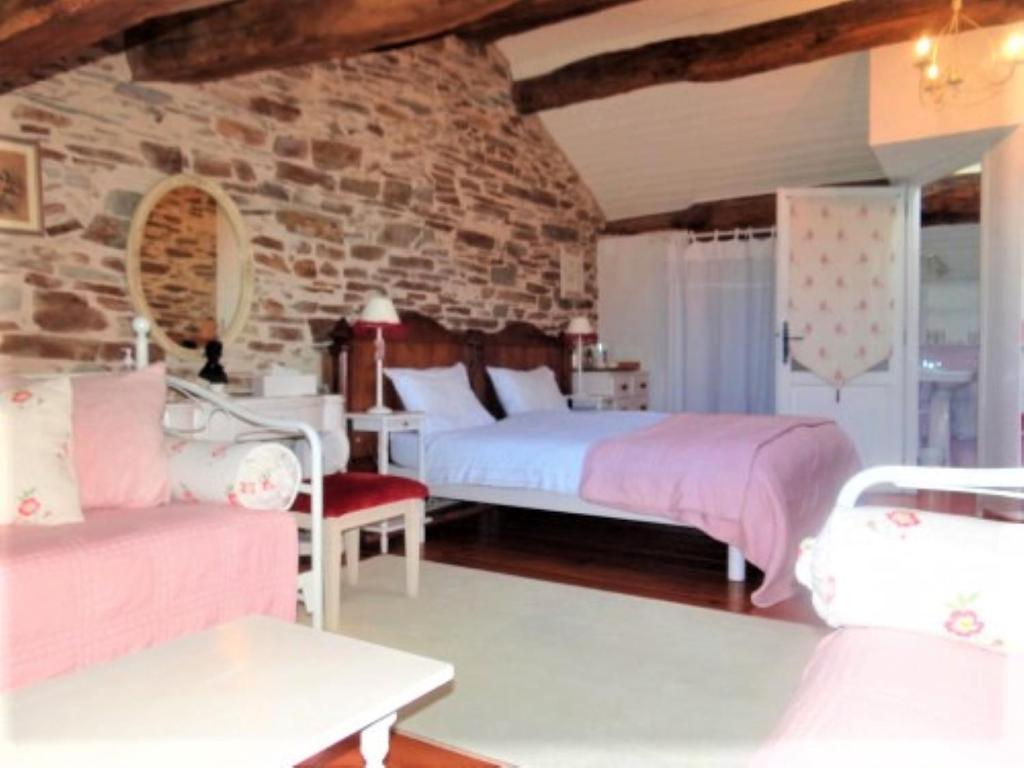 a bedroom with two beds and a stone wall at Chez Providence Chambres et Table d'Hôtes in Cuxac-Cabardès
