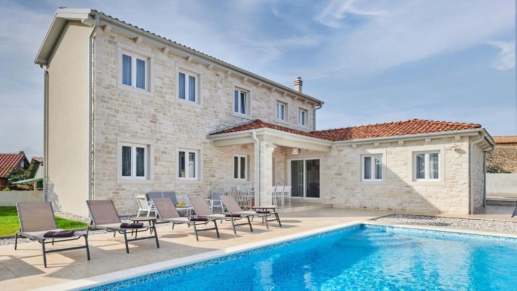 a villa with a swimming pool in front of a house at Villa Leon in Brtonigla