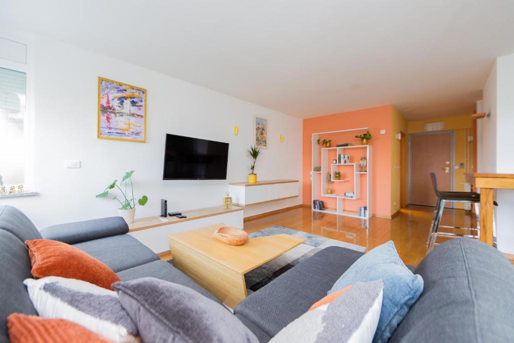 ein Wohnzimmer mit einem blauen Sofa und einem Tisch in der Unterkunft Apartman Bruna SELF CHECK-IN in Osijek