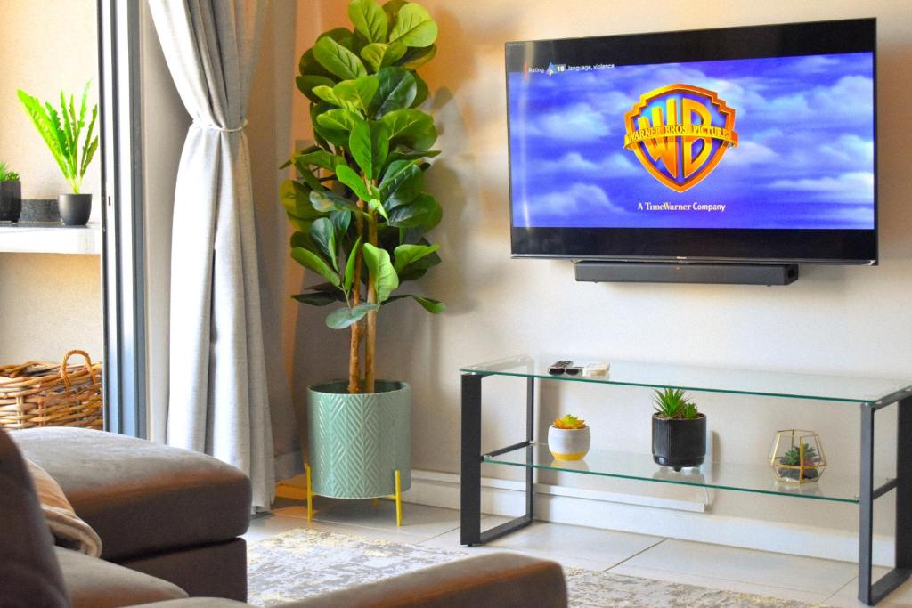 a living room with a flat screen tv on a wall at Red Velvet - Lux One Bedroom in Pretoria