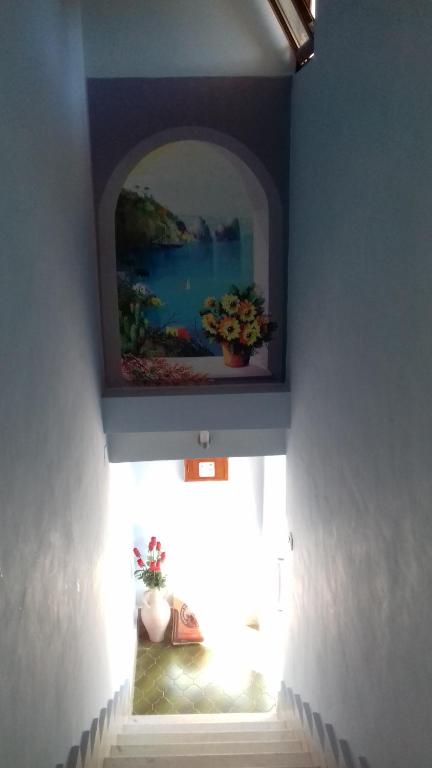 eine Wand mit einem Gemälde darauf mit einem Regal mit Blumen in der Unterkunft beb Business Mini Appartamento in Casalnuovo di Napoli