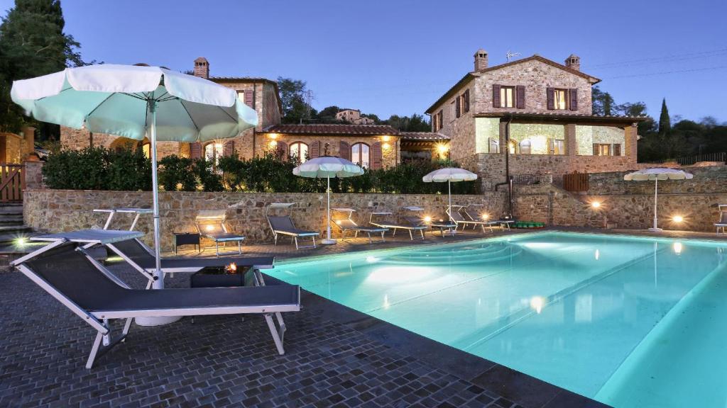 uma piscina com duas cadeiras e um guarda-sol em La Vecchia Fonte 15, Emma Villas em Volterra