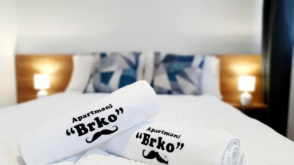 Una cama con sábanas blancas y almohadas. en Apartmani Brko, en Kotor-Varoš