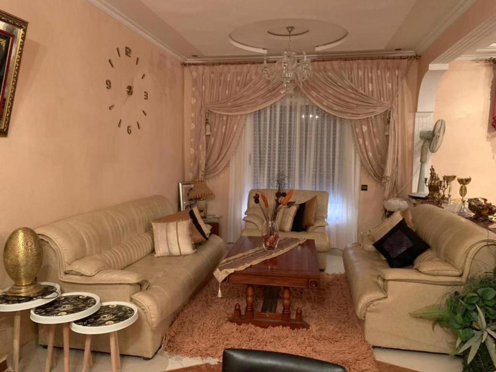 ein Wohnzimmer mit Sofas, einem Tisch und einer Uhr in der Unterkunft Comfortable home in middle Atlas in Azrou