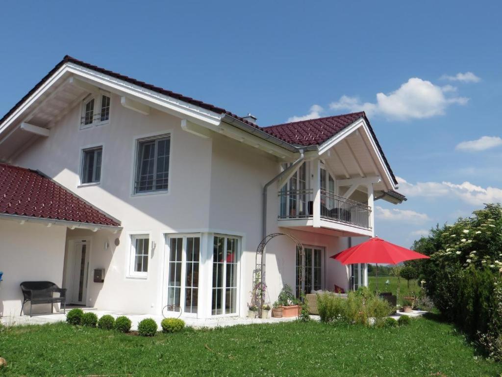 a white house with a red umbrella in the yard at Ferienwohnung am Golfplatz in Grassau