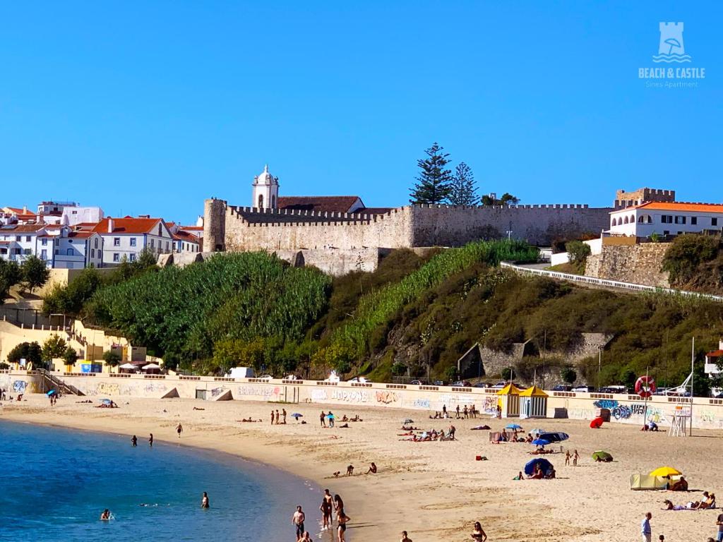 a group of people on a beach with a castle at Beach & Castle - Sines Apartment in Sines