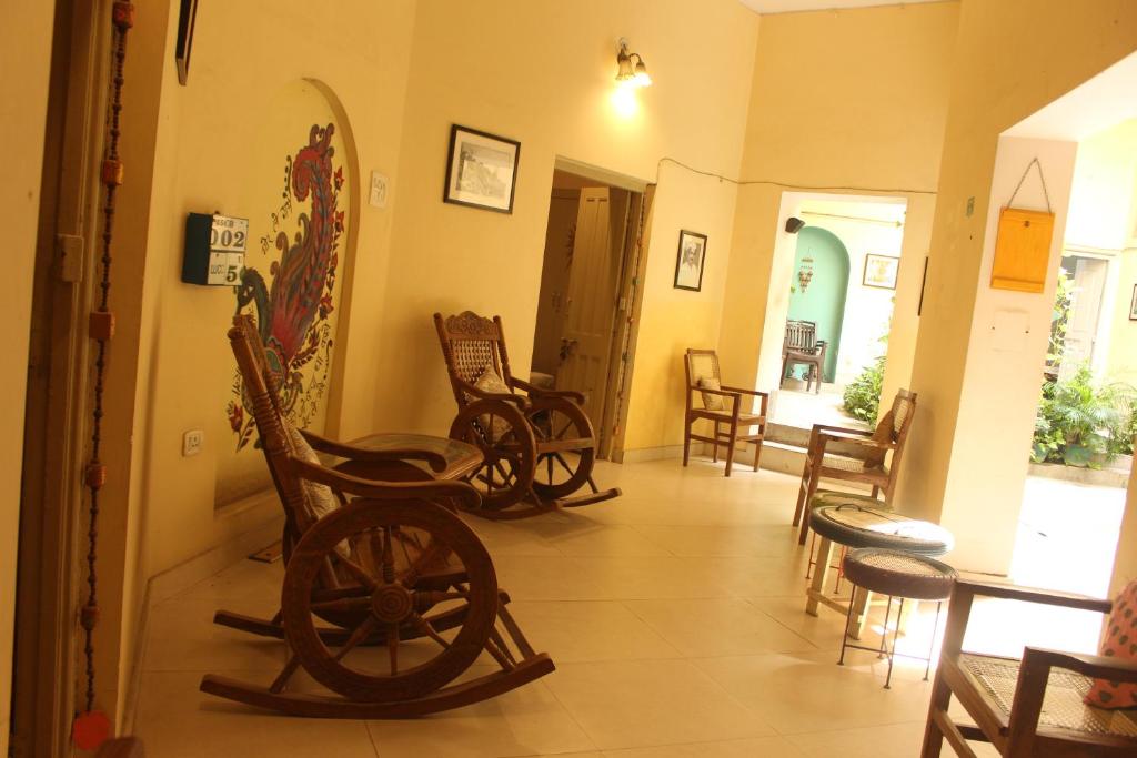 um quarto com cadeiras de madeira e uma mesa num quarto em Cozy Inn em Varanasi