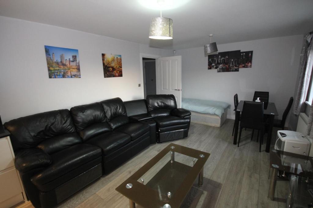 a living room with a black leather couch and a table at Holden Court Apartments -Apt 4 in West Drayton