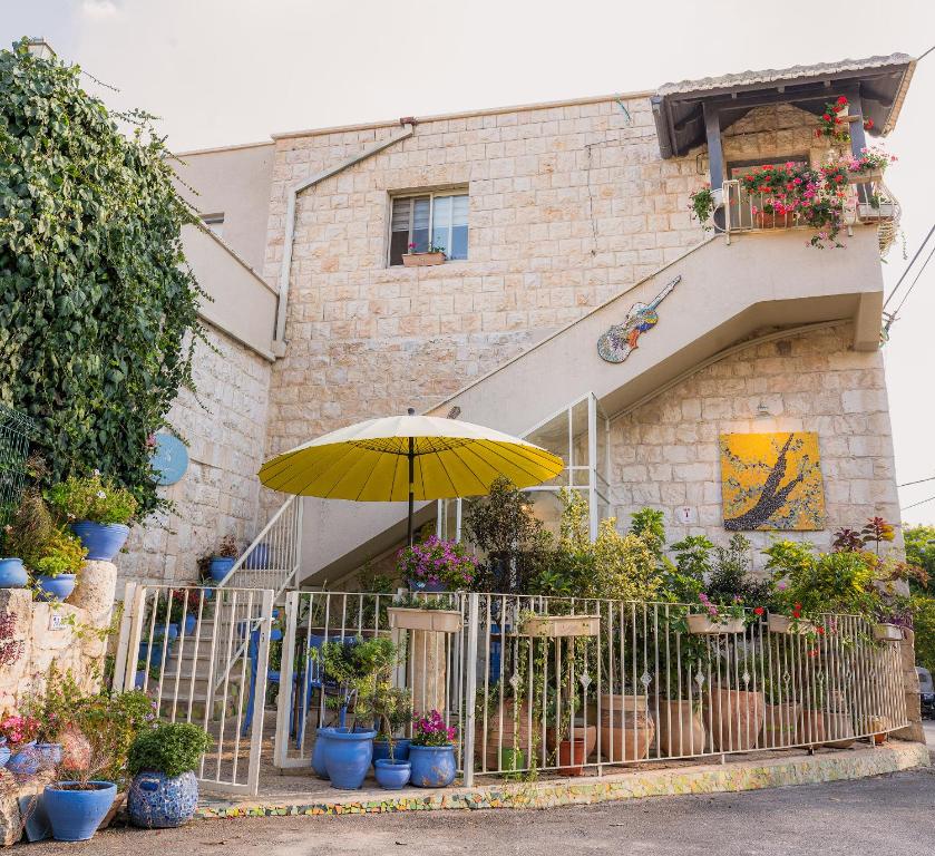 a yellow umbrella in front of a building with plants at Khalil lane in the Village in Mi‘ilyā