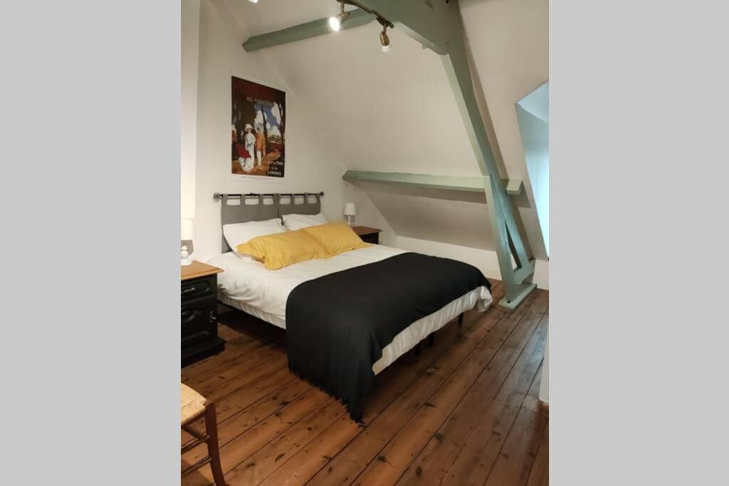 een slaapkamer met een bed en een houten vloer bij La Maison de Valy in Montreuil-sur-Mer