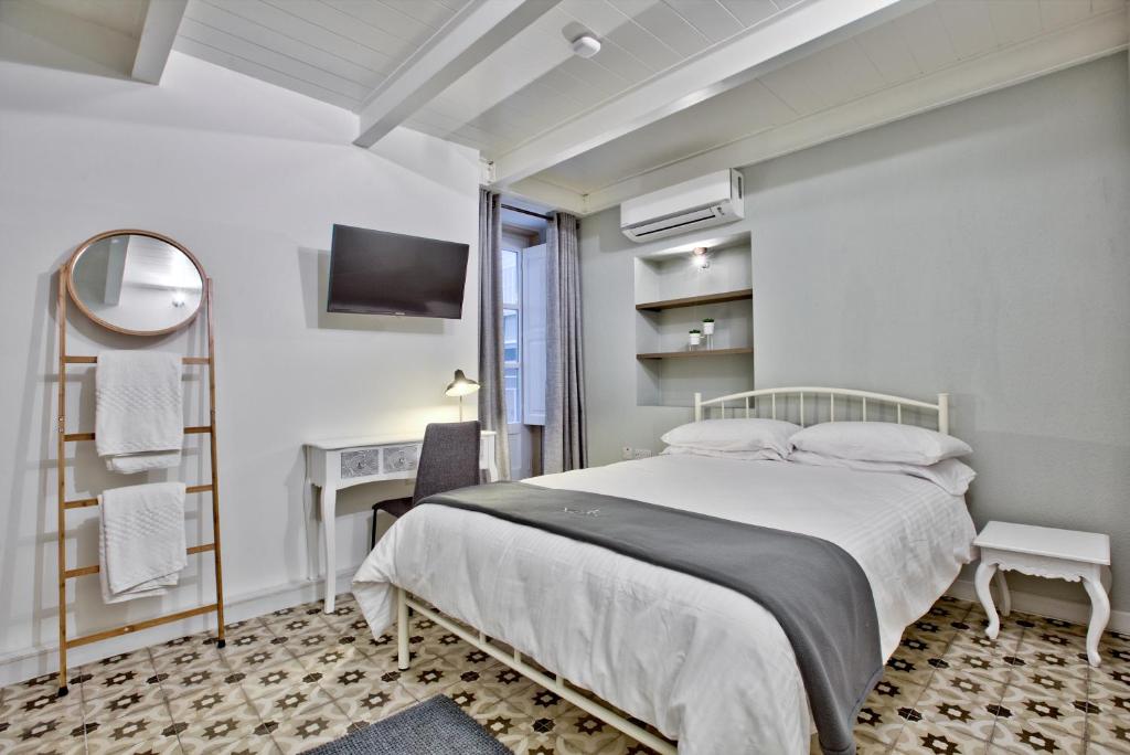 a white bedroom with a bed and a desk at Chateau La Vallette - St. Elmo Suite in Valletta