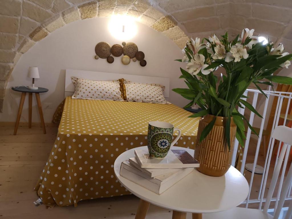 1 dormitorio con 1 cama con un jarrón de flores sobre una mesa en Seasons Home San Foca en San Foca