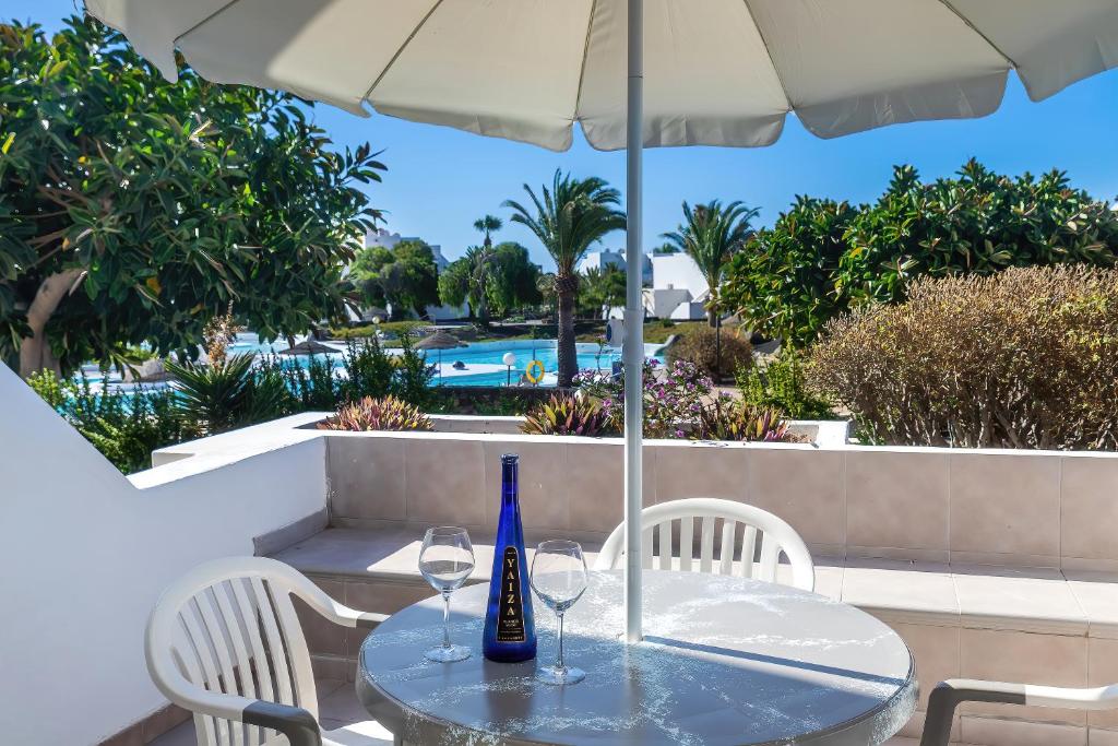 a table with two wine glasses and an umbrella at La Joya del Molino. Vistas a la Piscina, 1hab, A/C in Costa Teguise