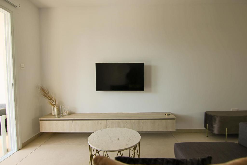 uma sala de estar com televisão numa parede branca em Phaedrus Living Seaview Flat Limnaria 154 em Pafos