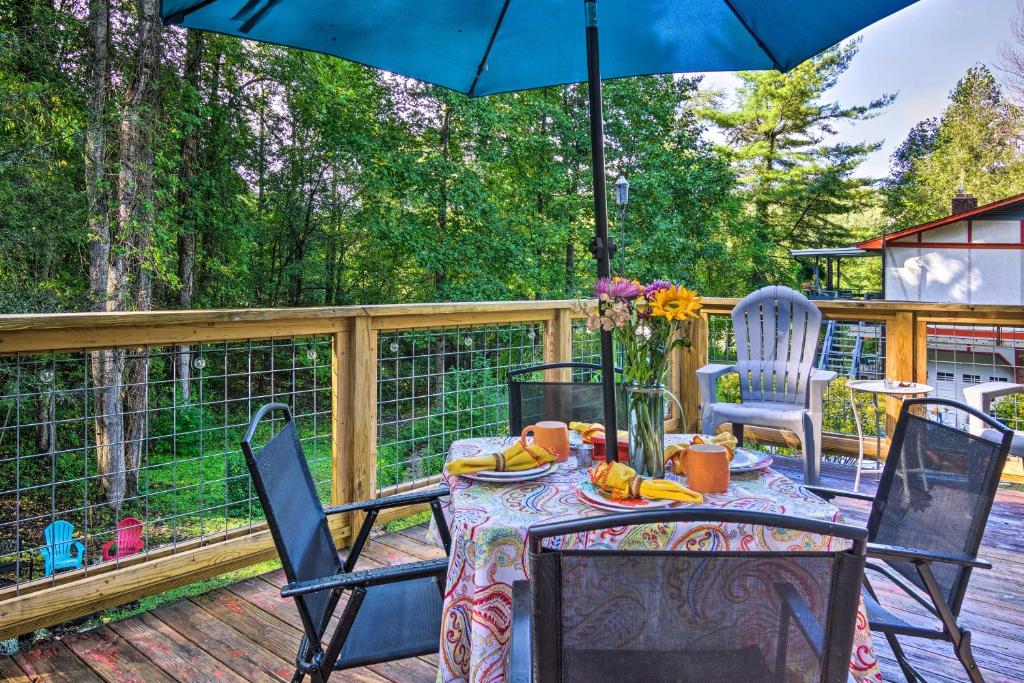 una mesa y sillas en una terraza con sombrilla en Shaw Creek Cottage with Fire Pit and Forest Views, en Hendersonville