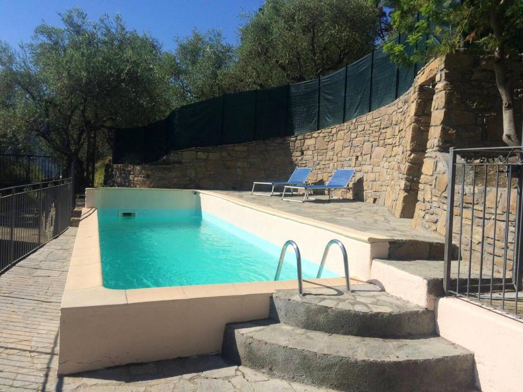 uma piscina com duas cadeiras e uma cerca em Villa de 4 chambres avec piscine privee terrasse amenagee et wifi a Breil sur Roya em Breil-sur-Roya