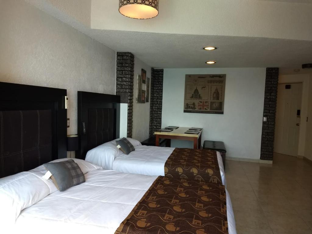 Habitación de hotel con 2 camas y escritorio en SUITE CON VISTA AL MAR A PIE DE PLAYA, en Acapulco