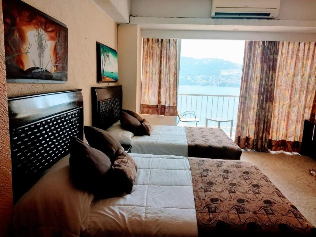 1 dormitorio con 2 camas y ventana grande en Suite en torres gemelas con vista al mar, en Acapulco