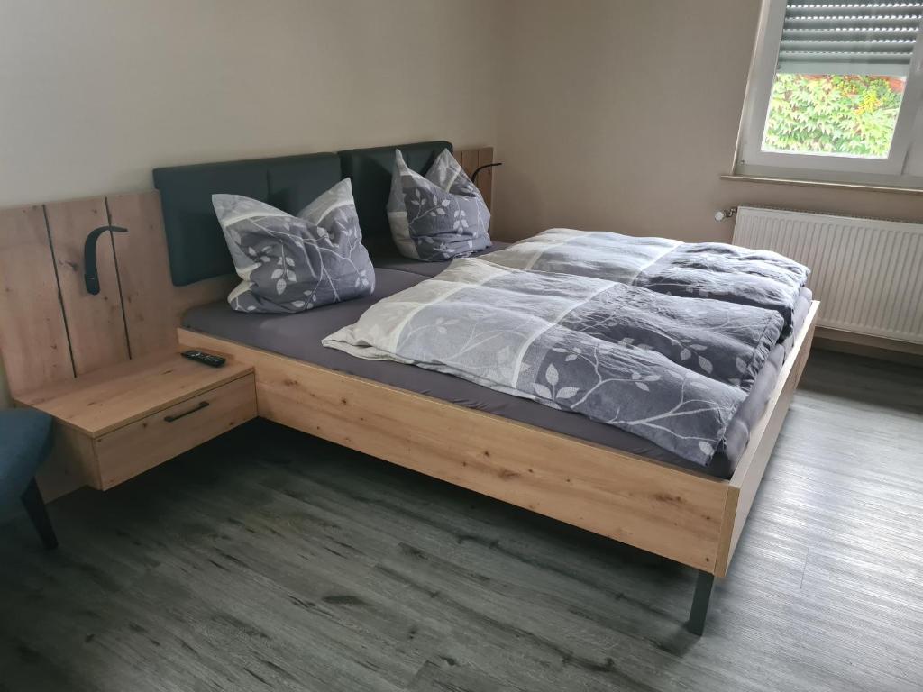 a bed with a wooden frame and pillows on it at Pension Im Wiesengrund Steinau Marborn in Steinau an der Straße