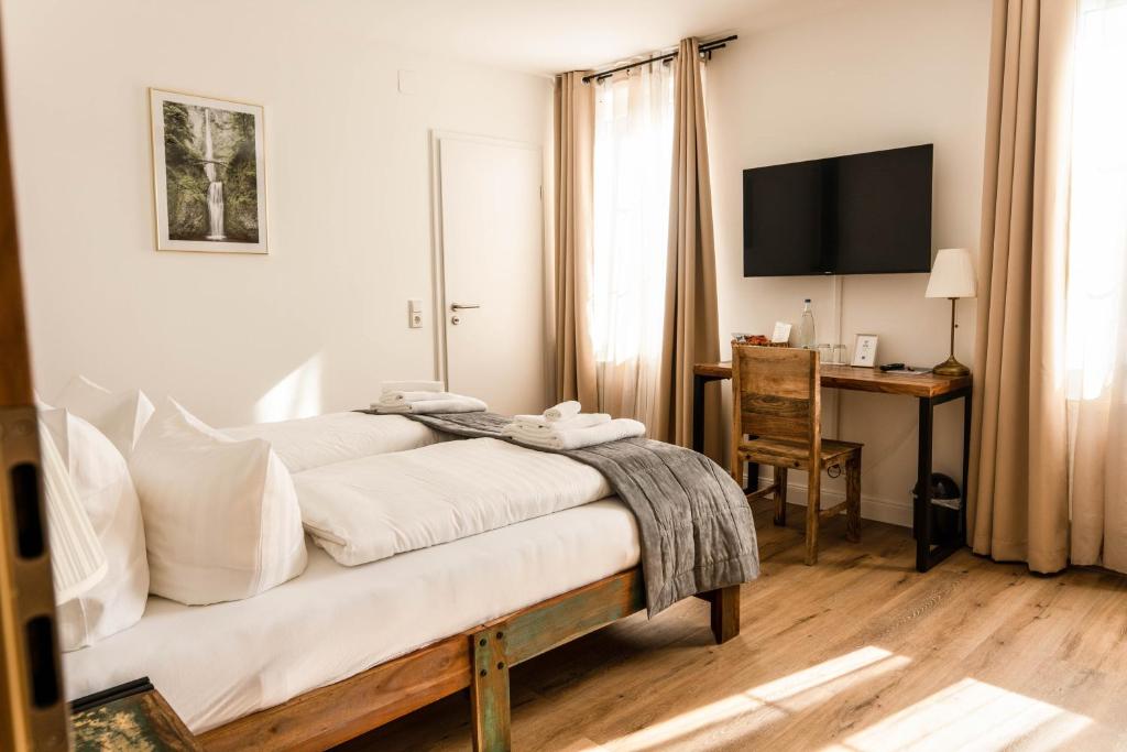 a bedroom with a bed with a desk and a television at RISA Hotel Village - Engel & Kreuz in Gaggenau
