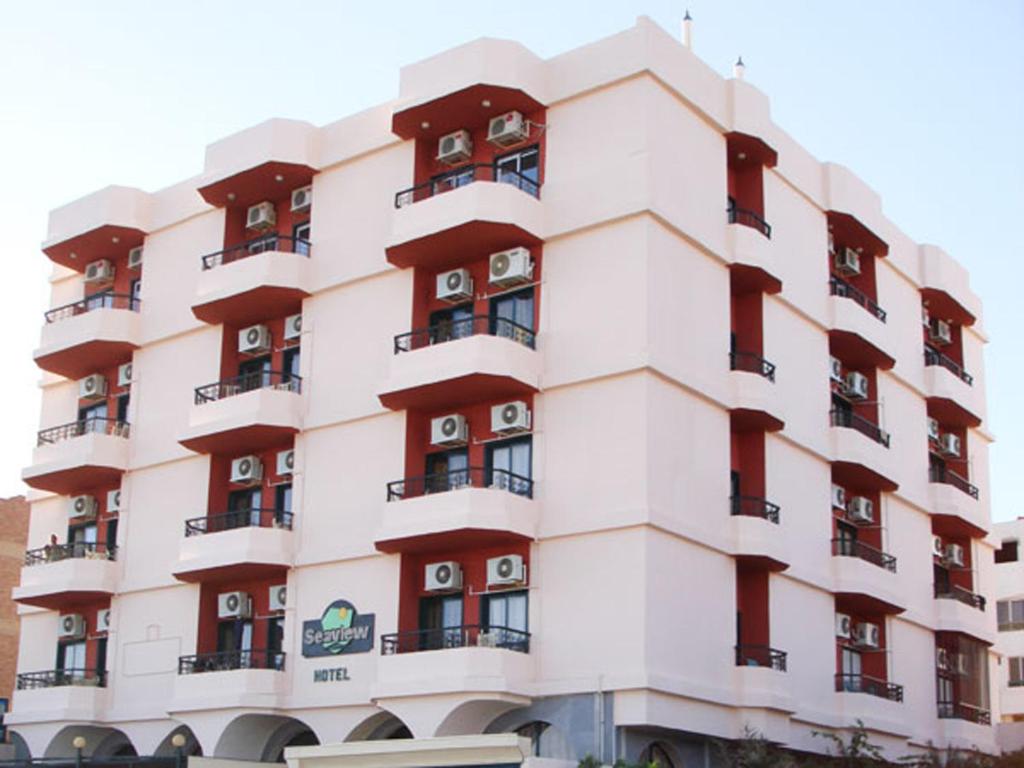 a large white building with red balconies at Sea View Hotel in Hurghada