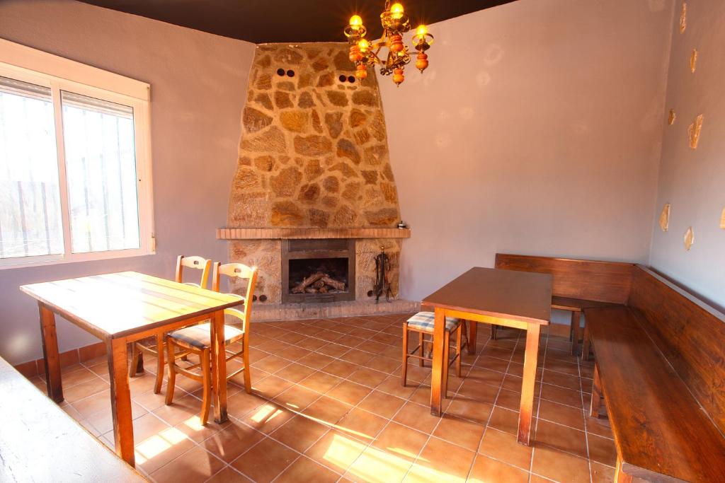 sala de estar con chimenea, mesa y sillas en Cuencaloft Villa del Tío Tomarro, en Villalba de la Sierra