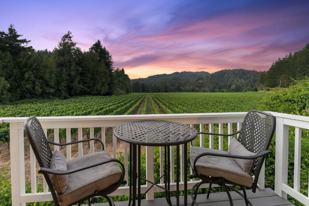 a table and chairs on a porch with a view of a vineyard at Melody Vineyard Cottage in Guerneville