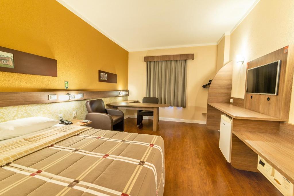 a hotel room with a bed and a desk at Hotel 10 São Leopoldo in São Leopoldo