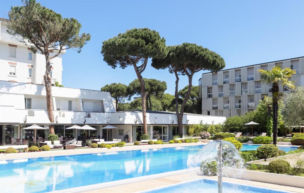 um hotel com piscina e árvores em Villa Regina - MarePineta Resort em Milano Marittima