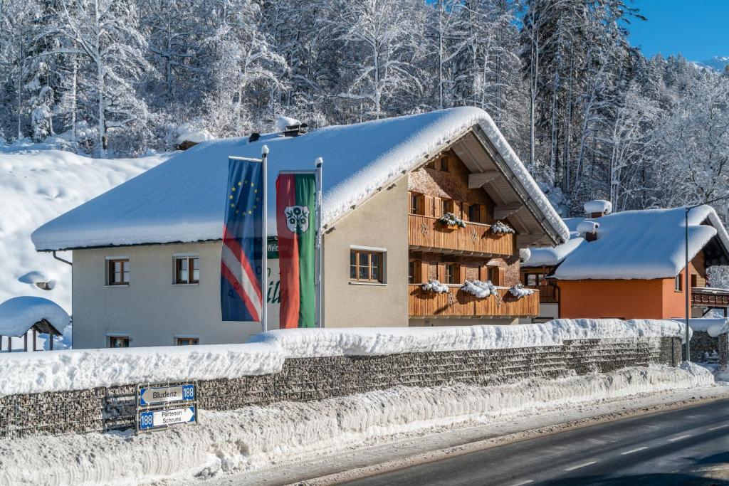 a building covered in snow next to a road at Hotel Pension Wilma in Schruns