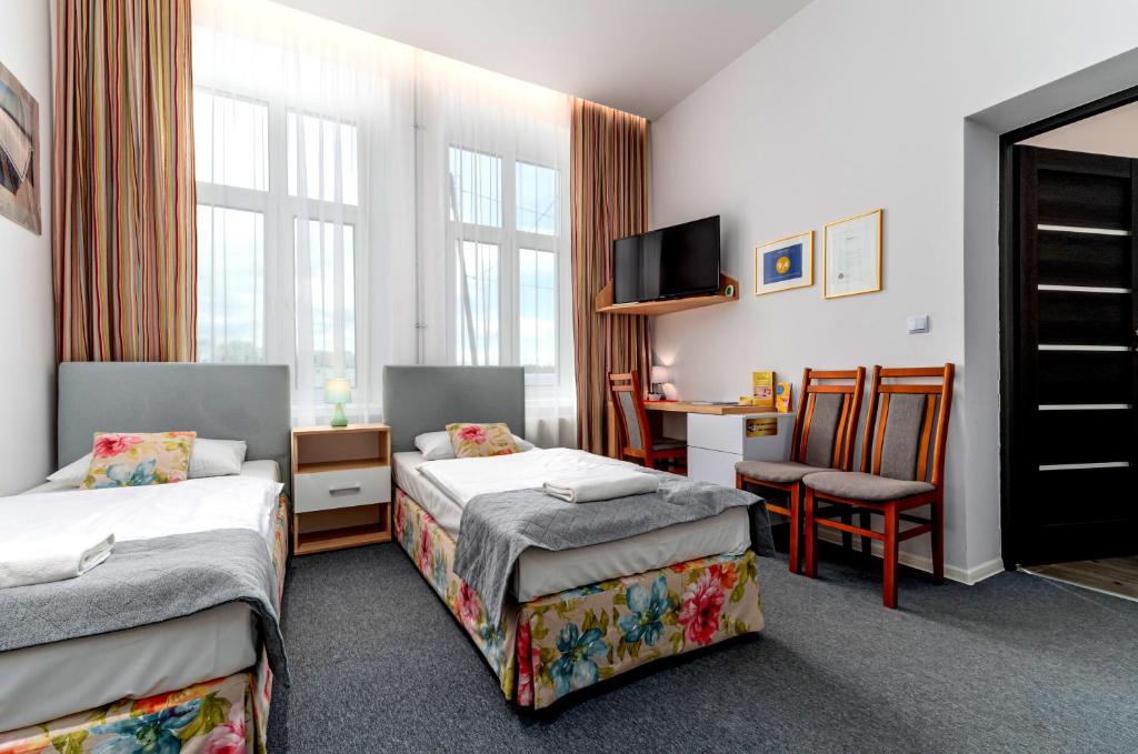 una habitación de hotel con 2 camas y una silla en Nasze Kamienice Apartament Express Rzeszów Główny, en Rzeszów