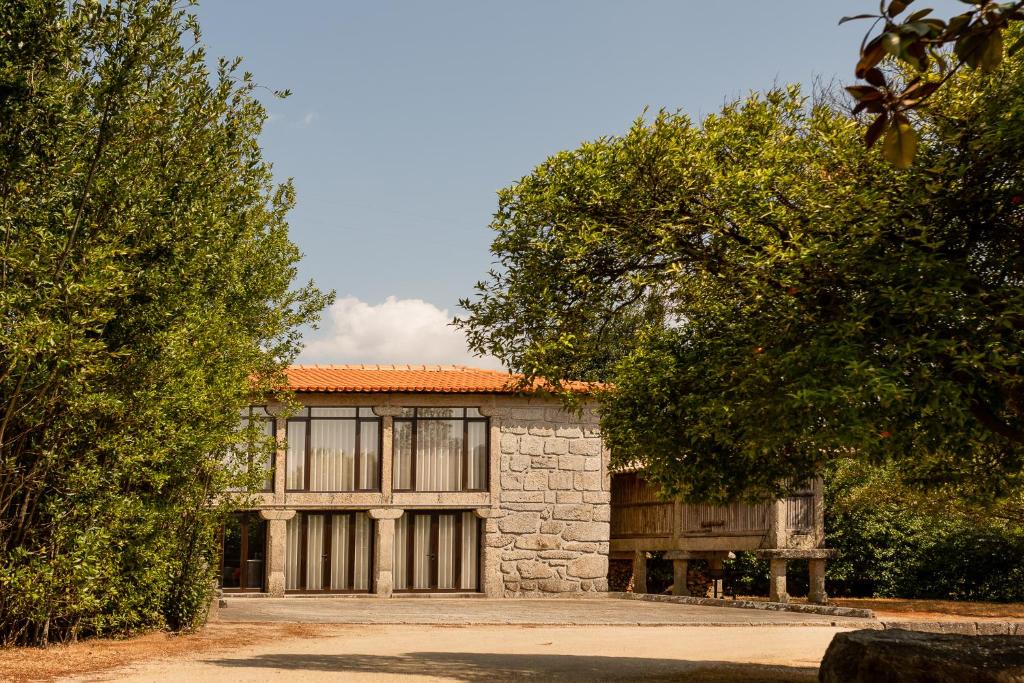 Casa da Eira - Alojamento Local في براغا: مبنى حجري بسقف برتقالي واشجار