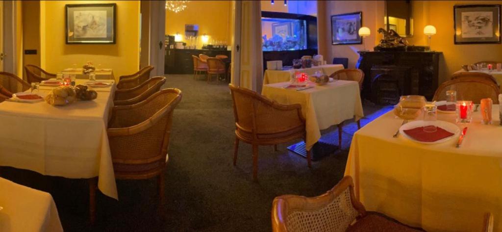 uma sala de jantar com mesas e cadeiras com toalhas de mesa brancas em Budget Hotel Le Beau Rivage em Middelburg