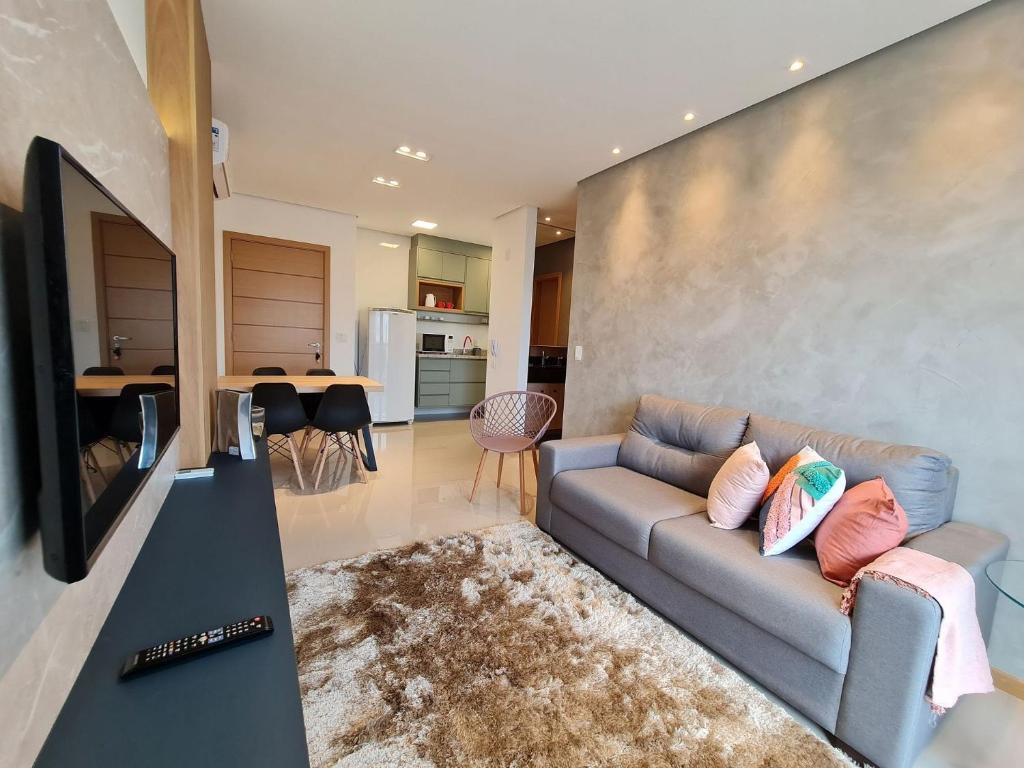 a living room with a couch and a kitchen at Apartamento Prime Master Collection in Passo Fundo