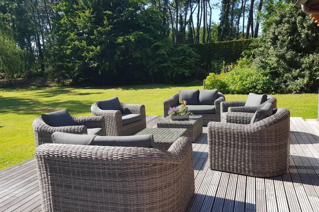 a group of wicker chairs and tables on a deck at Villa les Lutins in Le Touquet-Paris-Plage