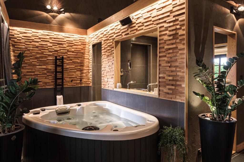 un bagno con grande vasca e specchio di Le Domaine des Prés Verts Suites & Chambres avec Jacuzzi Privatif à Châteauneuf a Châteauneuf