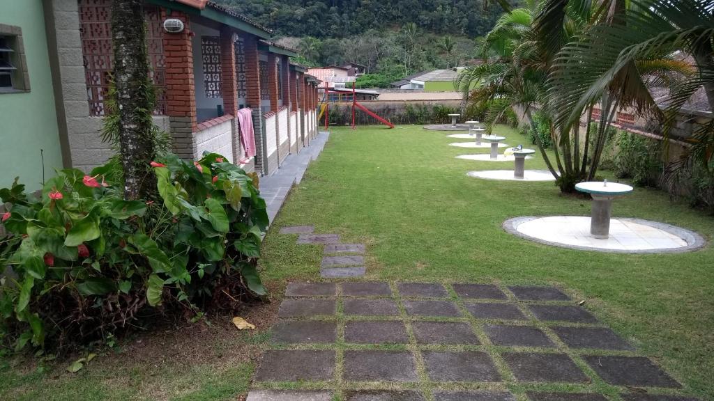 um jardim com um passadiço com um parque infantil em Chalés Luz Da Lua em Caraguatatuba