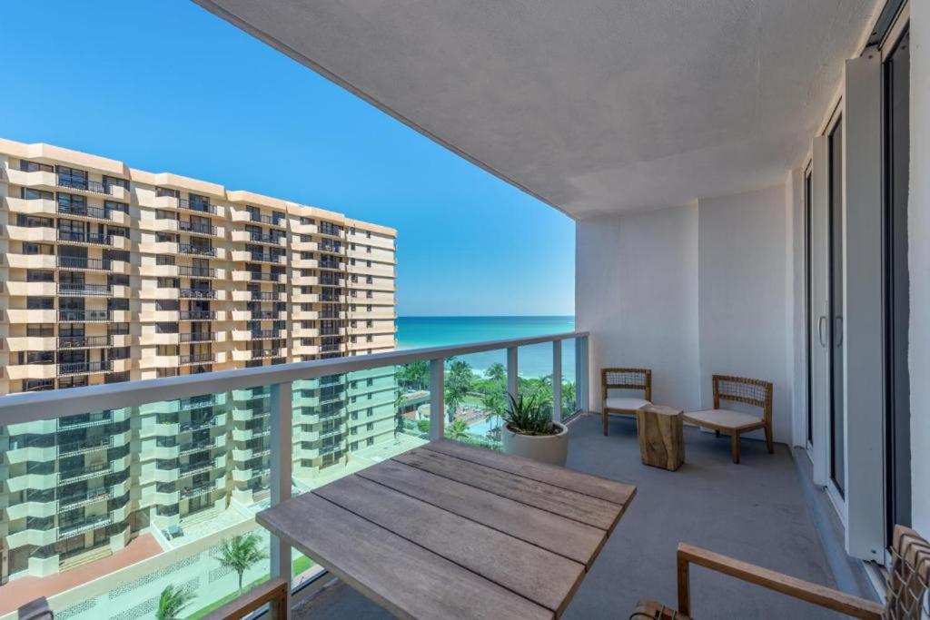 een balkon met een houten tafel en uitzicht op de oceaan bij 1 Hotel & Homes Miami Beach Oceanfront Residence Suites By Joe Semary in Miami Beach