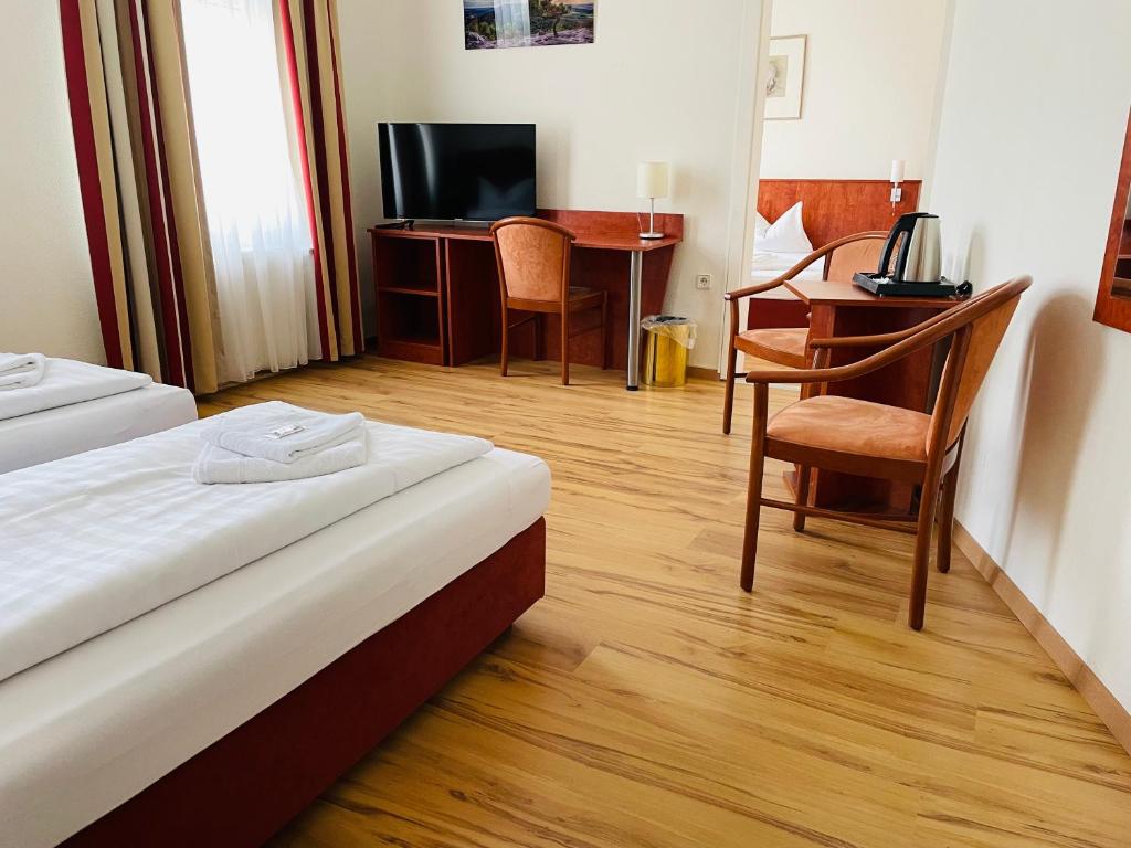 オッフェンバッハにあるホテル アム レーダームゼウムのベッド、デスク、テーブルが備わる客室です。