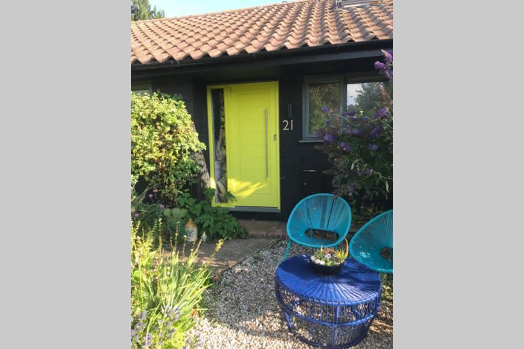 a garden with two blue chairs and a yellow door at The Yellow Door Whitstable - Peaceful retreat close to beach in Whitstable