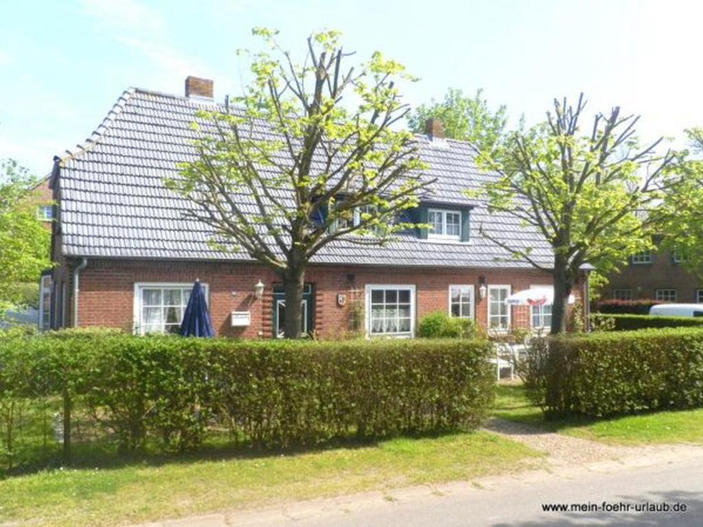 a red brick house with a black roof at Haus 94- Whg EG in Oldsum