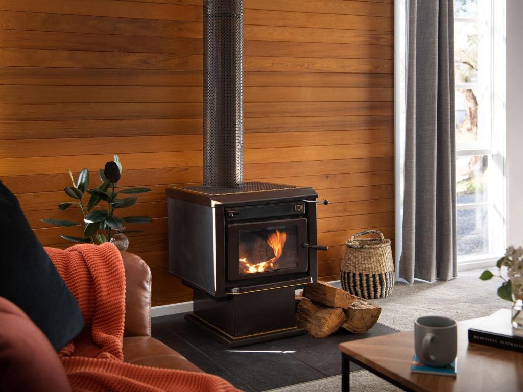 a wood stove in a living room with a couch at Lakewood minutes walk to Lake Daylesford in Daylesford
