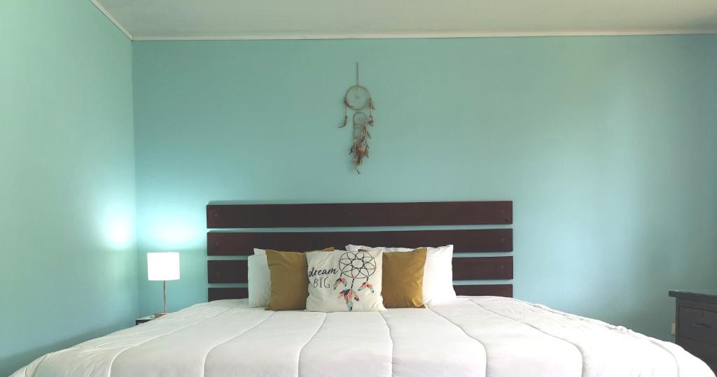 1 dormitorio con 1 cama grande y pared azul en Dreamcatcher house, en Sarchí