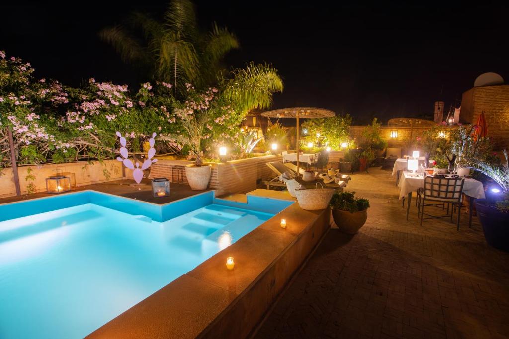 a swimming pool at night with a table and chairs at Riad Hizad in Marrakesh