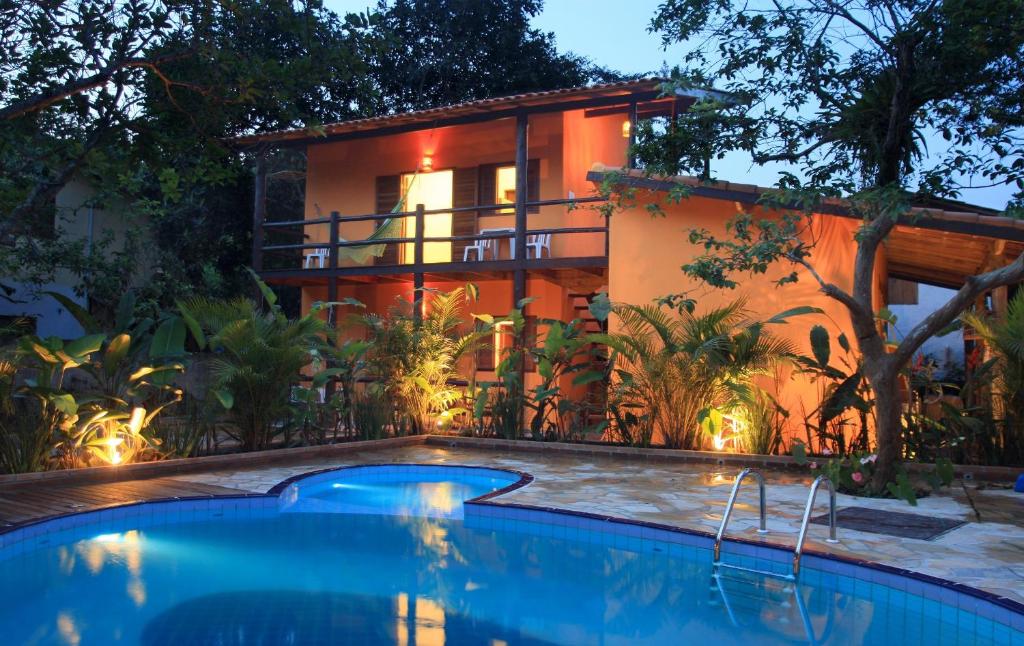 a house with a swimming pool in front of a house at Chalés e flats Recanto Primavera in Camburi