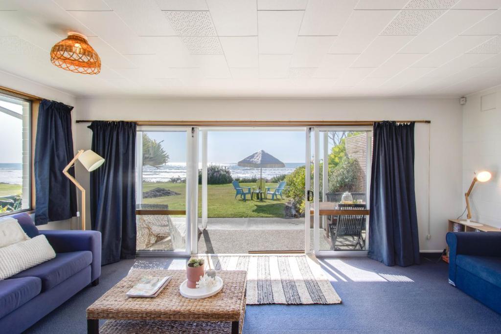 a living room with a blue couch and a view of the ocean at Absolute Beachfront - Waimarama Holiday Home in Waimarama