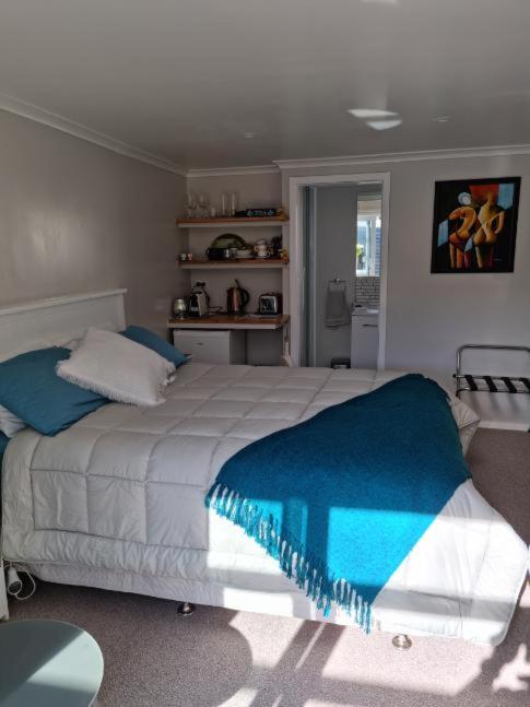 um quarto com uma cama grande e um cobertor azul em BnB on Carvell em Blenheim