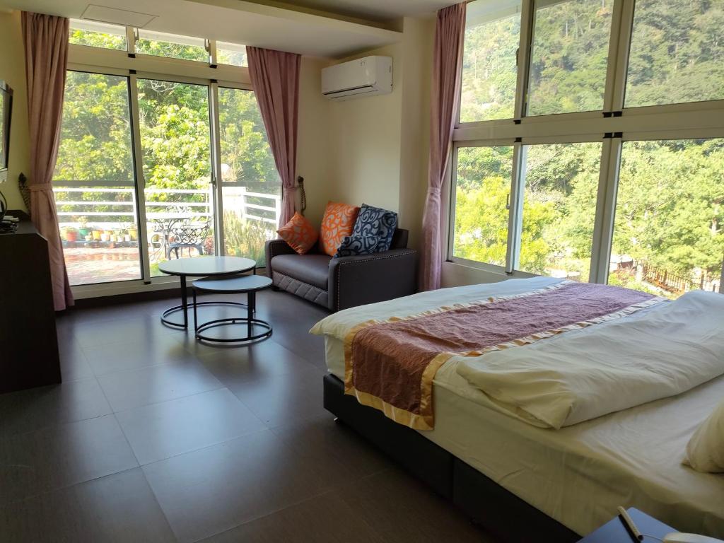 a bedroom with a bed and a couch and windows at Lily Village in Nanzhuang
