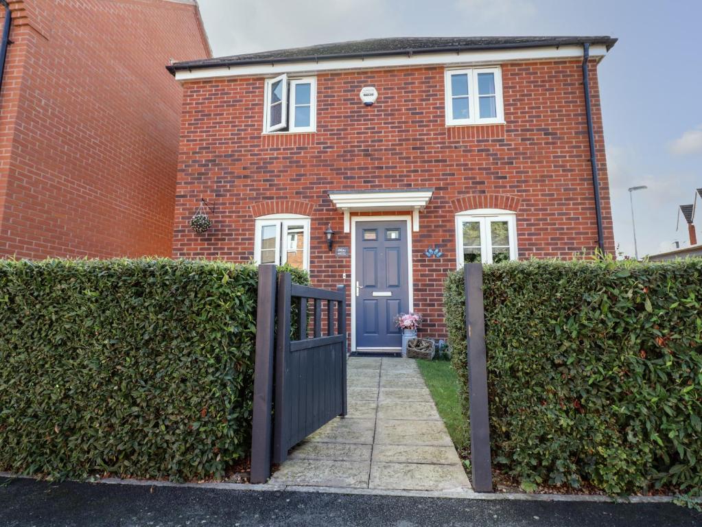 uma casa de tijolos vermelhos com uma porta azul em Robins Cottage em Evesham